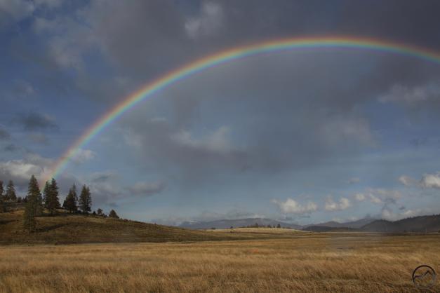 A rainbow arcs high above the Cascade Crest and the Shasta Valley.